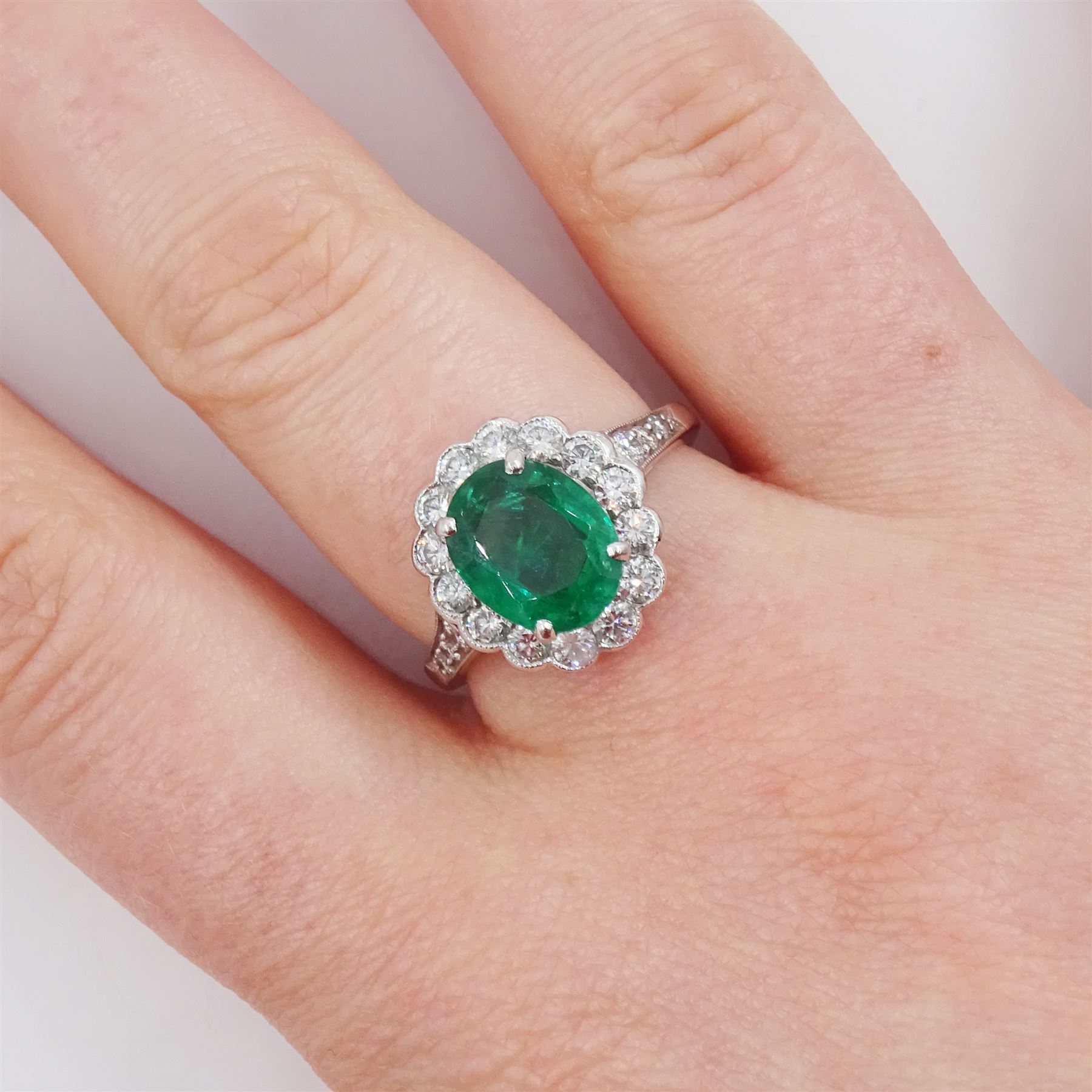 Platinum oval cut emerald and milgrain set, round brilliant cut diamond cluster ring, with diamond set shoulders, emerald approx 1.65 carat, total diamond weight approx 0.65 carat