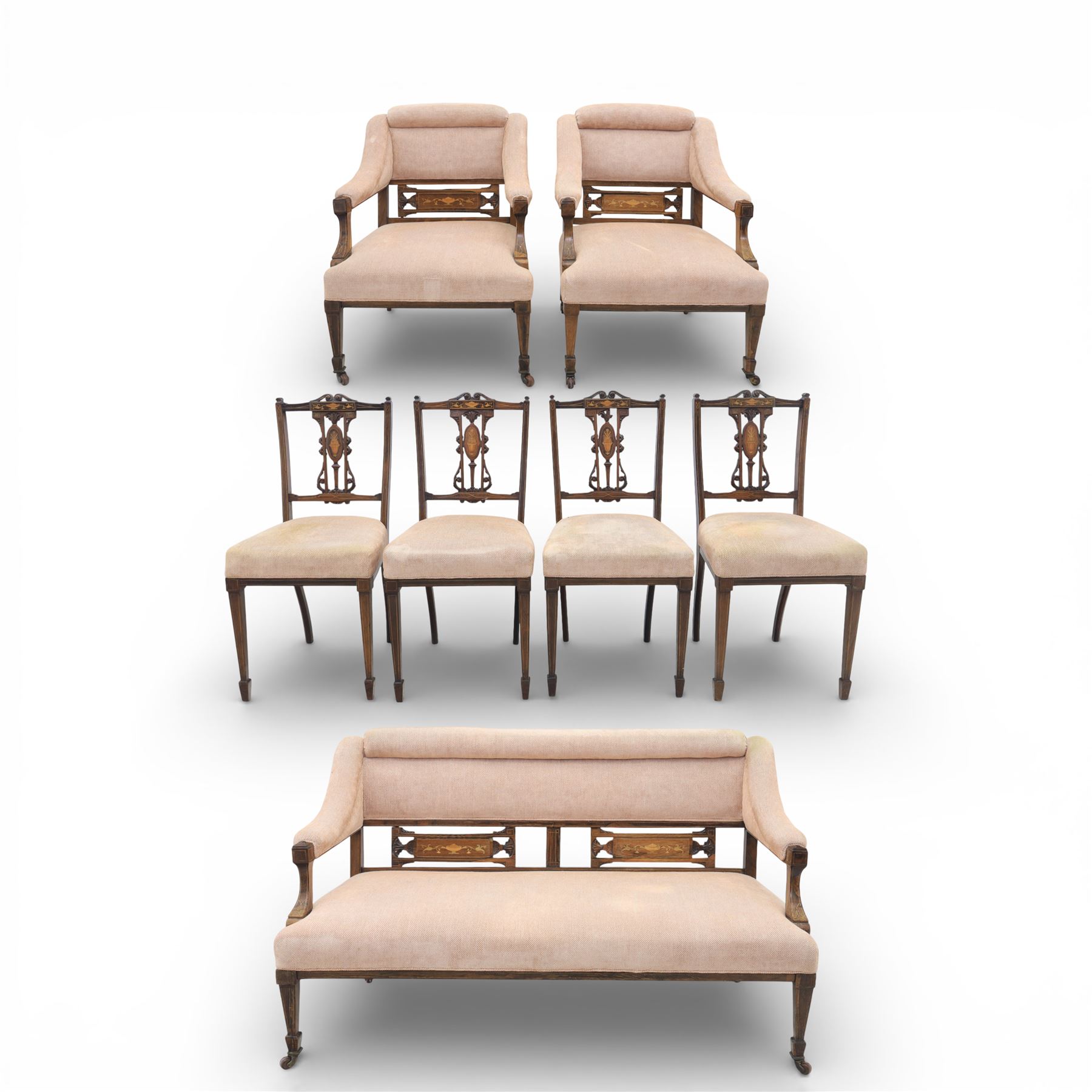 Quality Edwardian seven piece inlaid salon suite, comprising three seater settee, pair of arm chairs and four chairs with pierced splat backs, upholstered in pale pink fabric, inlaid with flowering urns, upon tapering legs with spade feet and castors
