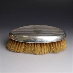 Five silver mounted dressing table items, including 1920s mirror and hairbrush set, with engraved initial to reverse, pair of clothes brushes with engraved initials and engine turned decoration and an oval clothes brush, all hallmarked 