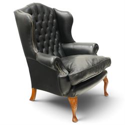 Pair of quality Georgian design wingback club armchairs, the high arched back with wings over rolled arms, upholstered in back-buttoned black leather with loose seat cushion, raised on foliate carved cabriole supports