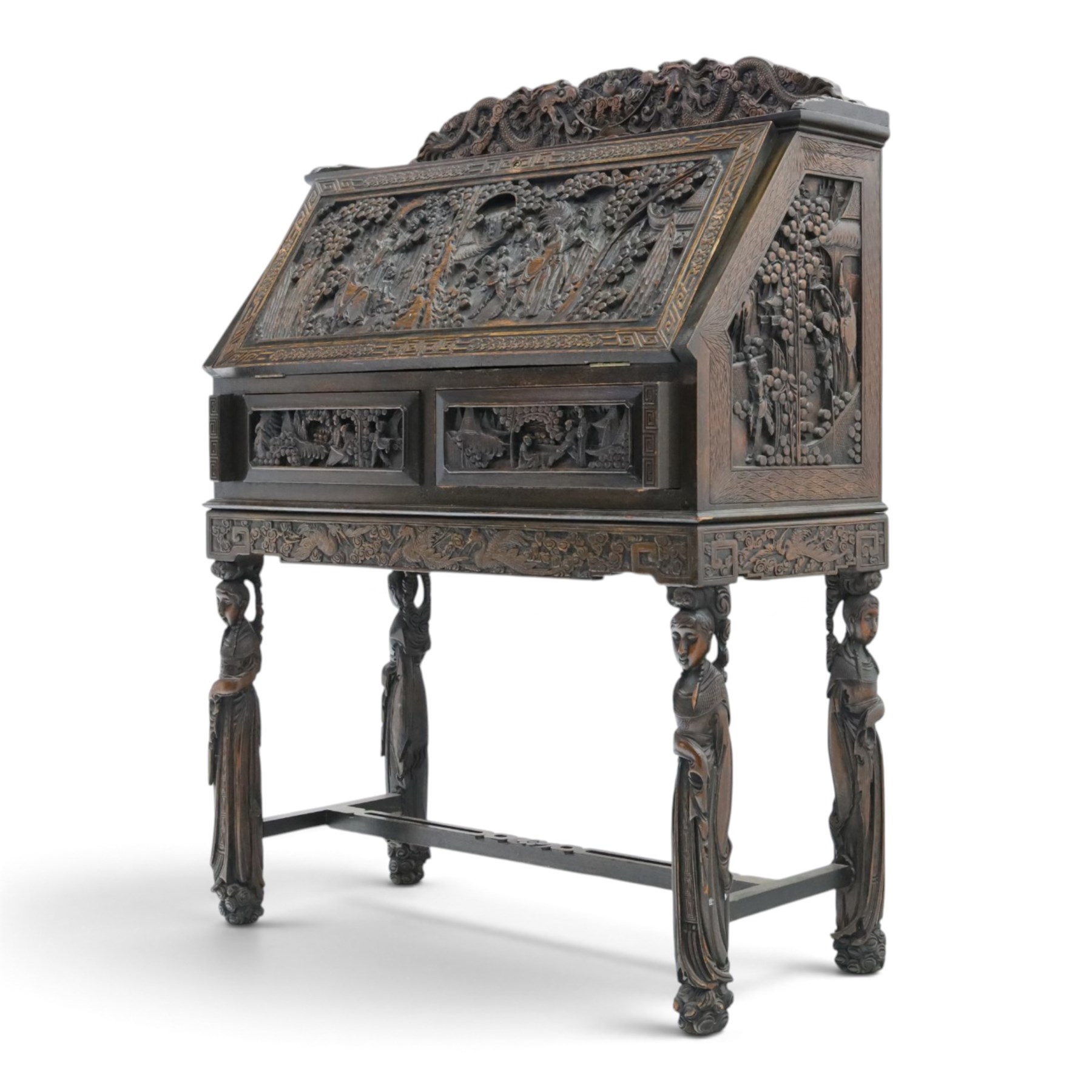 Early 20th century Chinese export carved hardwood writing bureau, the sloped fall front deeply carved with a narrative figural scene beneath pine and prunus trees, above a pair of rectangular carved panels, the shaped crest rail with entwined dragons, interior fitted with pigeonholes and a central drawer, on figural front supports with shaped stretcher