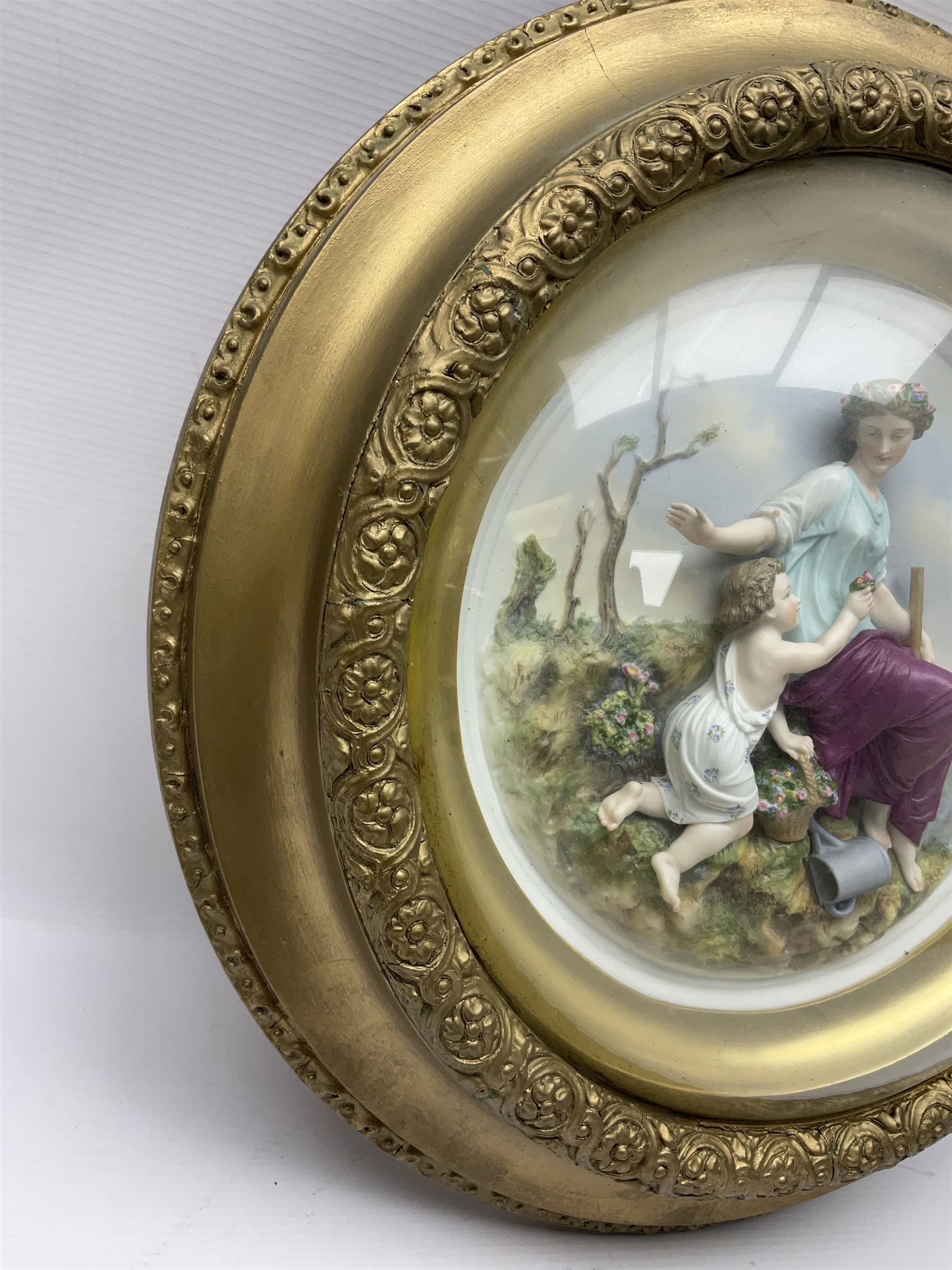 Set of four early 20th century Continental bisque plaques, each of circular form, modelled in high relief as the Four Seasons personified, within gilded circular frames under convex glass, overall D44.5cm
