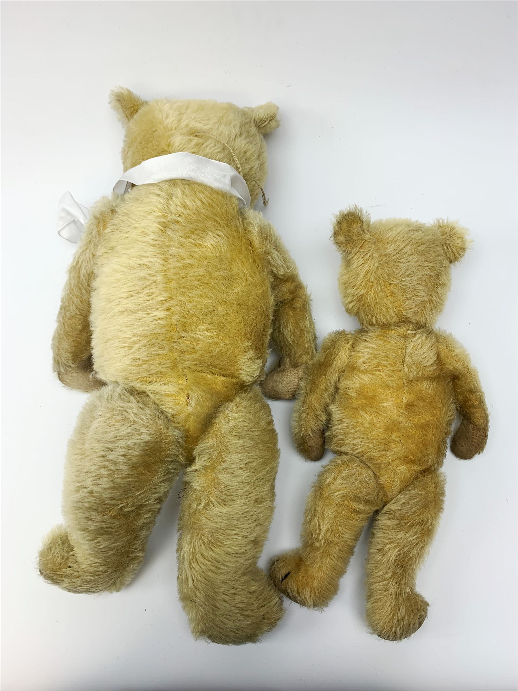 Two 1930s Chiltern type graduated teddy bears, one wood wool and one wood wool and kapok filled plush bodies, each with swivel revolving head, applied eyes and vertically stitched nose and mouth and jointed limbs, tallest H20.5