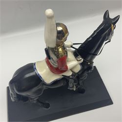 Mounted Lifeguard upon a black horse, in the style of Beswick, upon a wooden plinth, H31cm