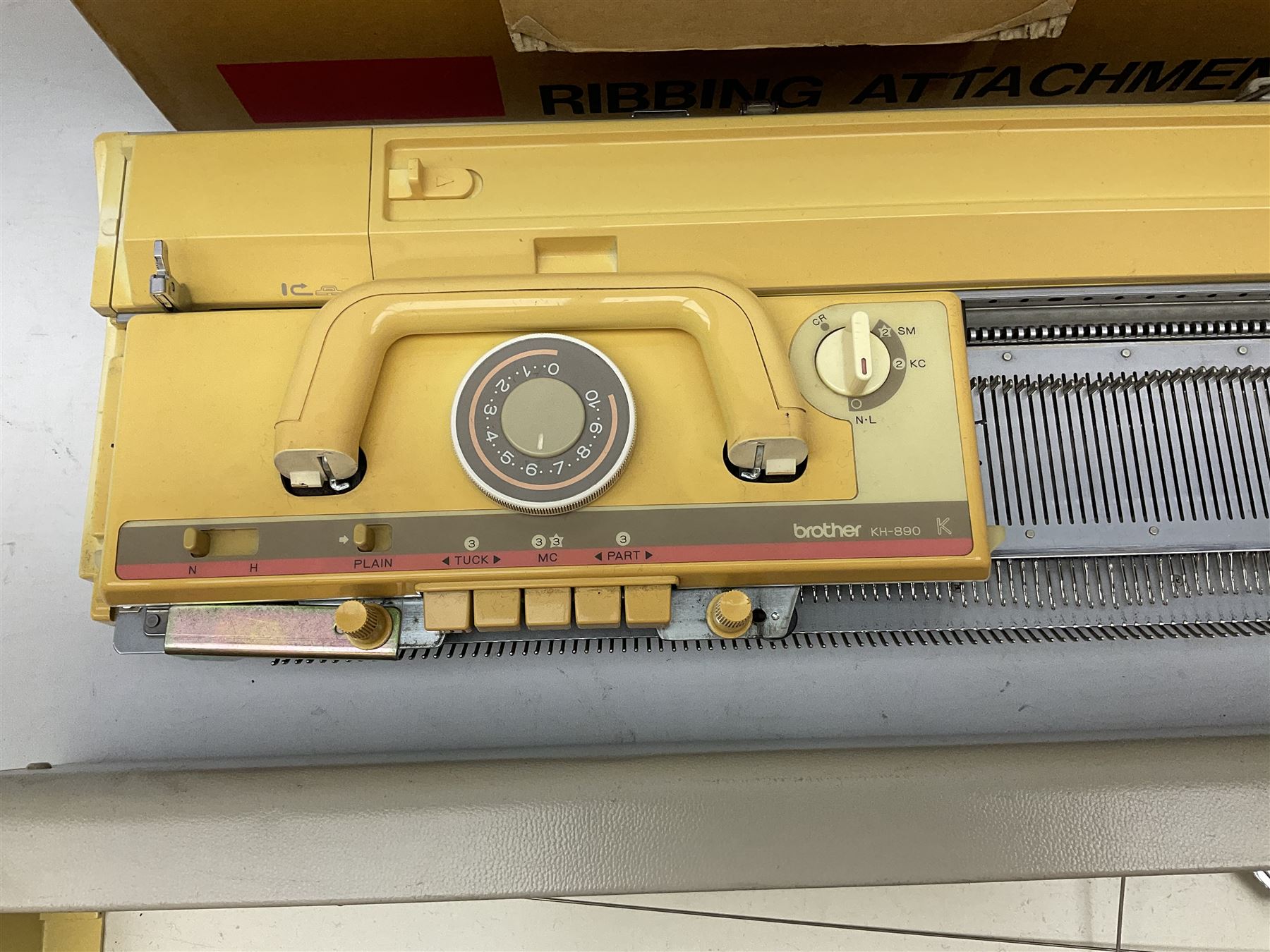  Brother cased knitting machine model KH-890 together with Brother Ribbing attachment model KH-850, knitting machine yarn cones in assorted colours, selection of knitting patterns etc