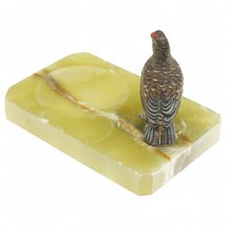 Cold painted bronze model of a grouse; mounted on an onyx ashtray base W11cm; together with an onyx cigarette box, W17cm, and horseshoe and perpetual calendar mounted on onyx slab, 205.cm x 14cm , each made out to Captain Charles Elsey upon his retirement from training Thoroughbred racehorses (3)
