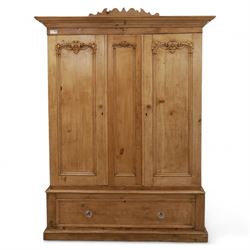 Late 19th century pine wardrobe, with stepped cornice over triple panelled doors, applied foliate carvings to outer panels, raised over a separate pine plinth drawer with moulded facia and twin glass pulls
