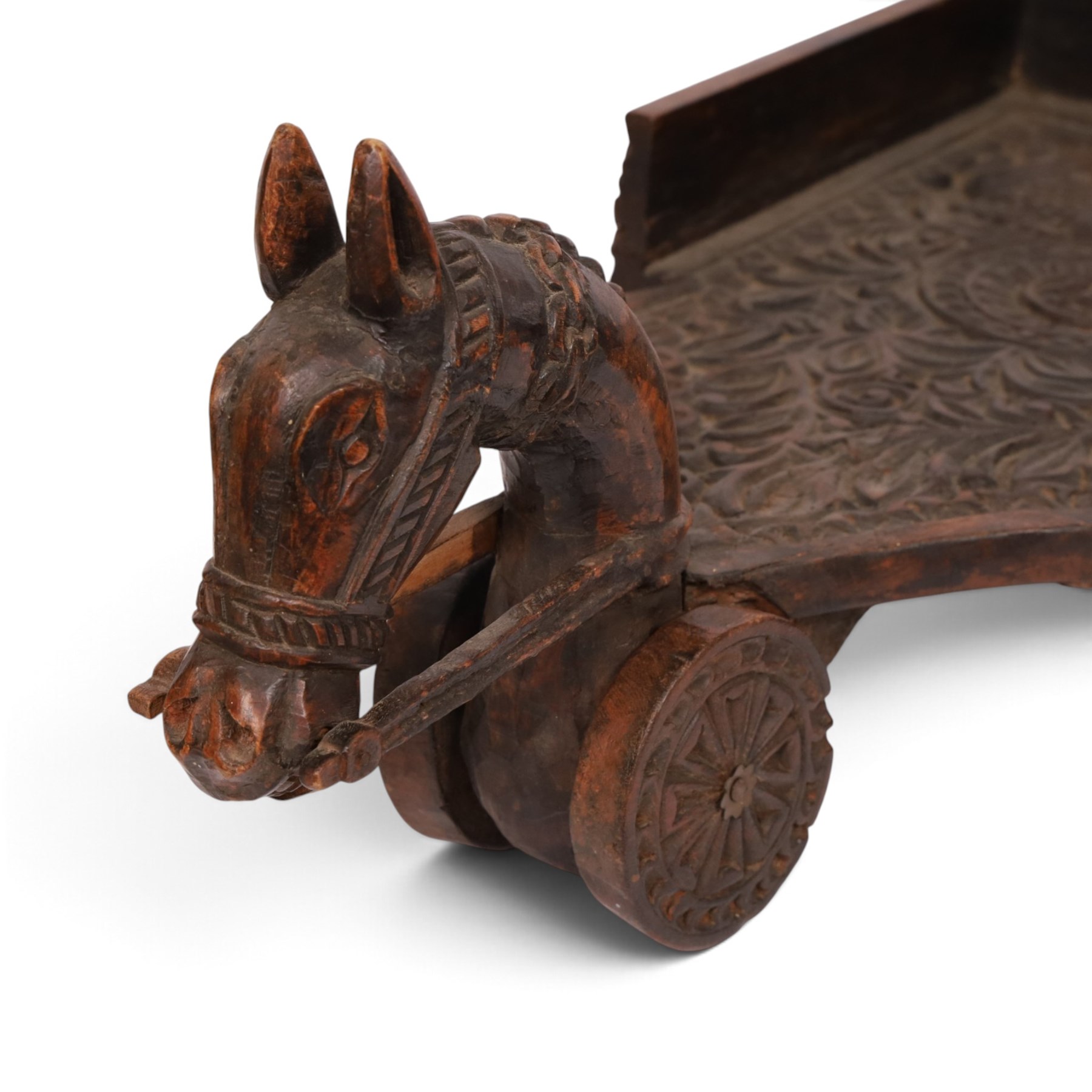 Indian carved wooden tray on wheels, the front carved as a horses head, the cart with foliate details, H28cm