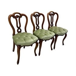 Set of six carved Victorian walnut balloon back dining chairs, button upholstered in green velvet fabric, back with foliate carved decoration supported on scroll form legs 