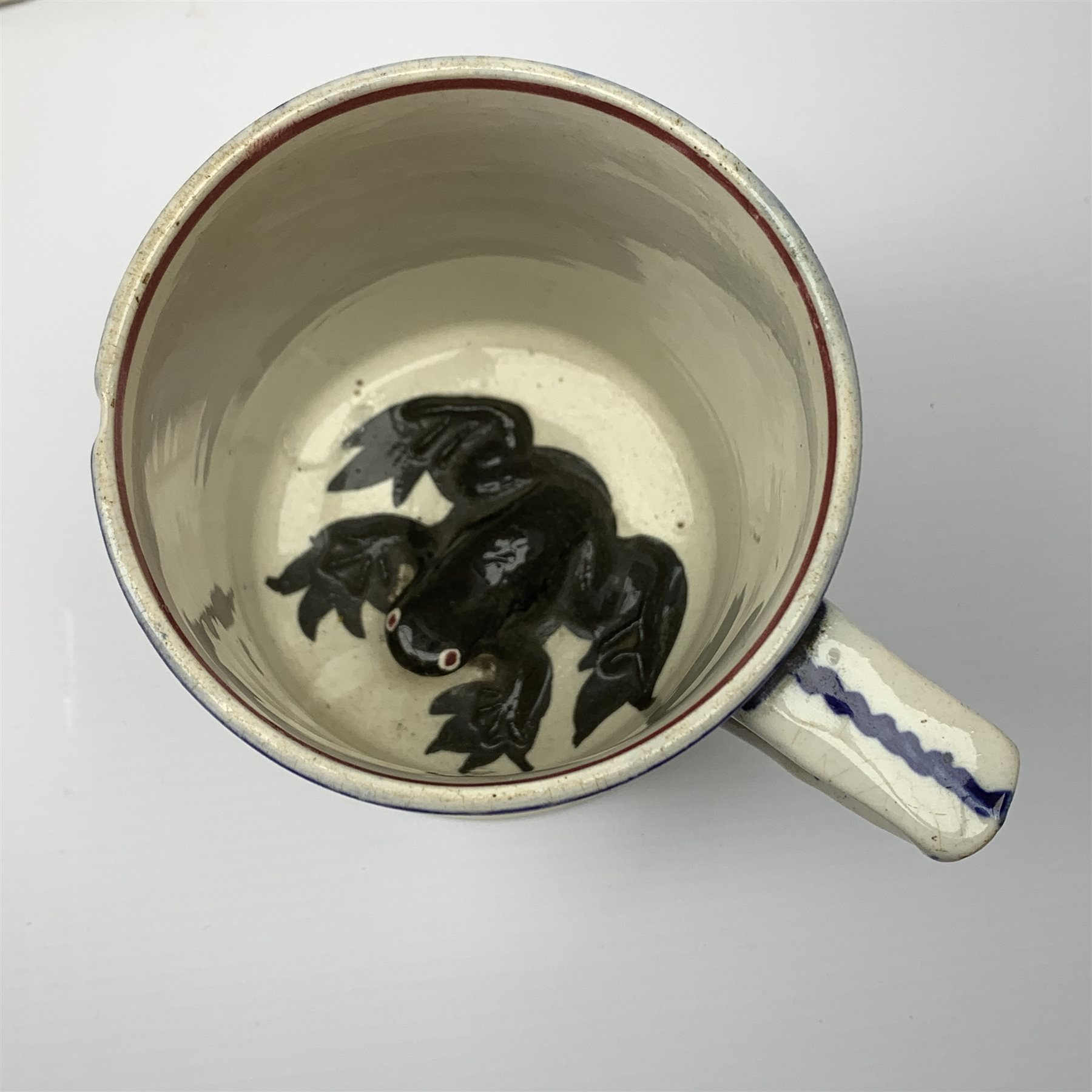 An early Victorian earthenware frog or surprise mug, decorated with printed and overpainted figural panels, H11cm, together with a 19th century child's plate detailed with a figural scene and inscribed Father Matthew administering the total abstinence pledge, 17.5cm, and a Staffordshire flat back figure seated upon a horse, H33cm. 