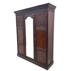 Late Victorian walnut triple wardrobe, projecting cornice over a acanthus carved frieze, central mirror glazed door flanked by two panelled doors relief carved with foliate urns, plinth base