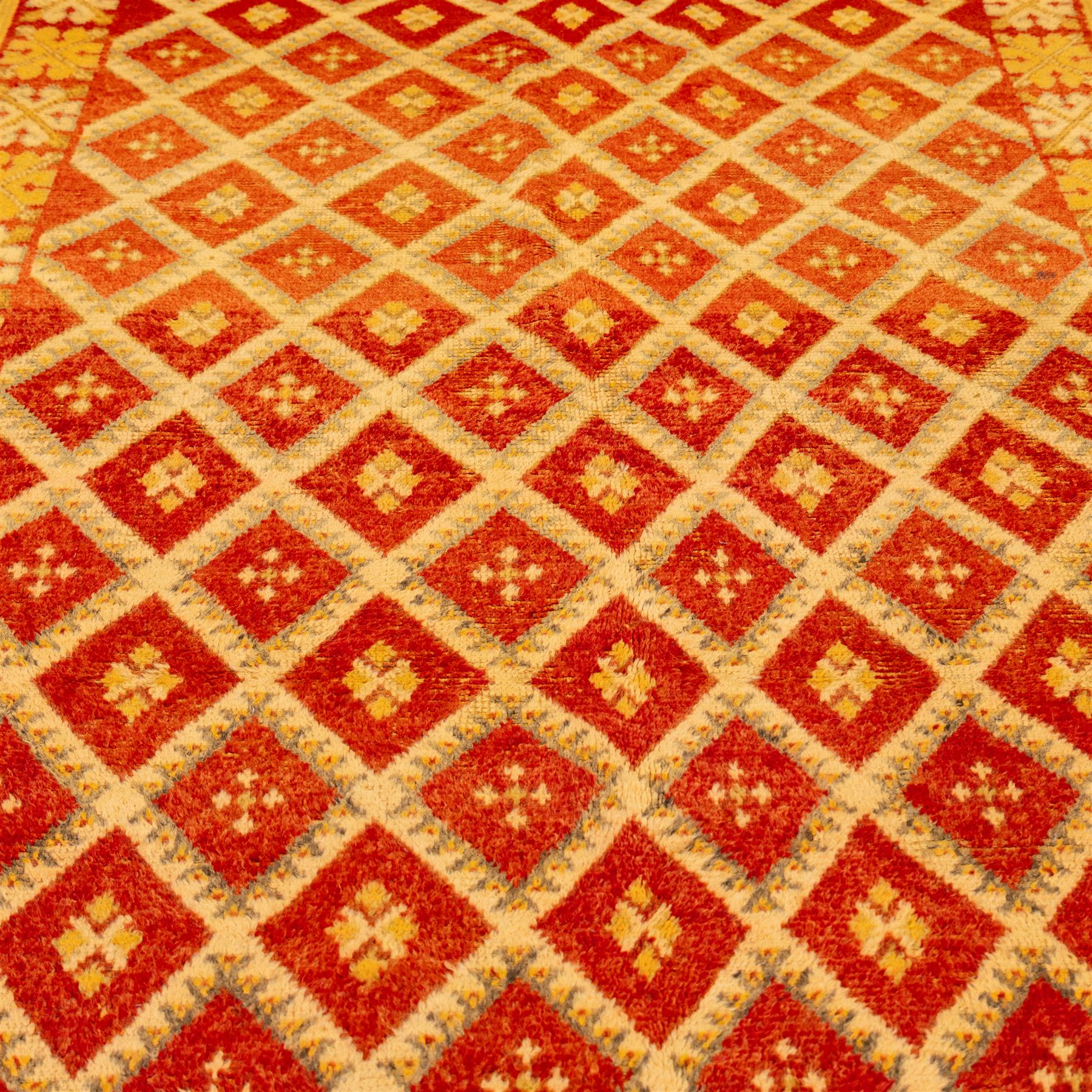 Moroccan Berber hand knotted runner, the red and orange ground woven with an all over lattice of lozenge motifs enclosing small geometric devices, within narrow patterned borders, finished with fringe to one end
