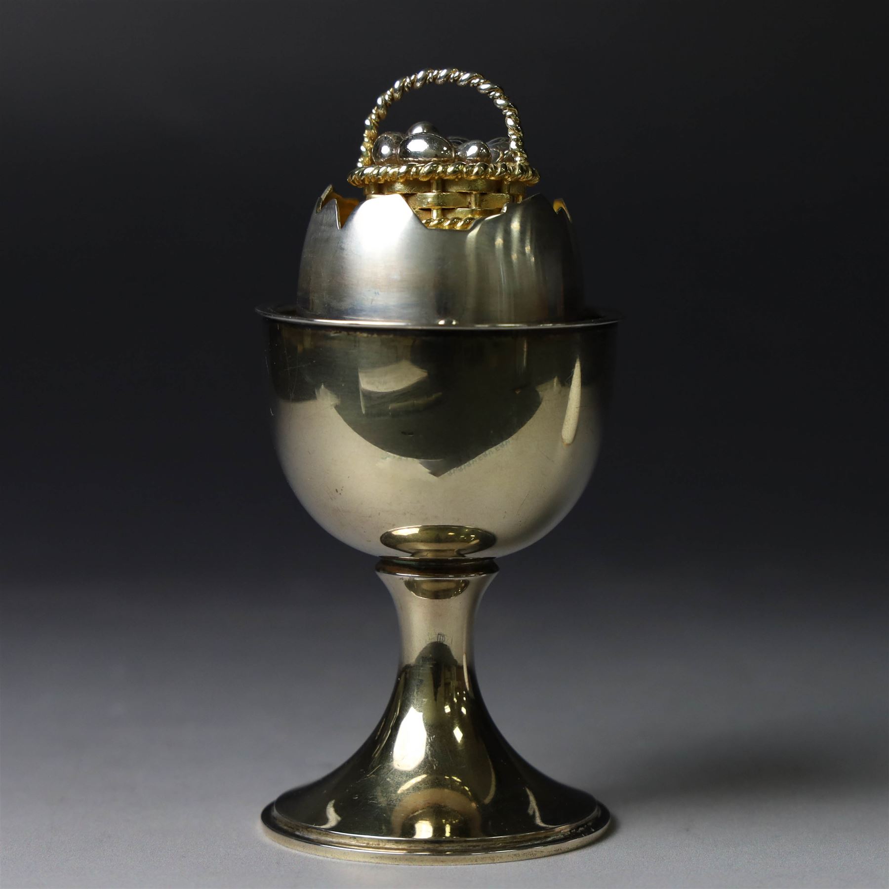 Late 20th century silver-gilt novelty surprise egg by Anthony Gordon Elson, the egg cup containing a  removeable shell, lifting to reveal a parcel gilt egg basket beneath, hallmarked Anthony Gordon Elson, London 1979, H11cm