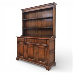 Georgian style oak dresser, the moulded cornice above two open plate racks, upon base with rectangular top above an arrangement of three frieze drawers fitted with brass swan neck handles, and three panelled cupboard doors, upon bracket feet