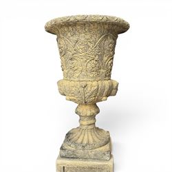 Pair of George III design antiqued composite stone garden urns of campana form, the egg-and-dart everted rim over a waisted body relief moulded with scrolling fruiting foliage and flowerheads, the gadrooned underbelly with twin mask ornaments, the knopped stems on fluted socles, raised on faux panelled square pedestal bases