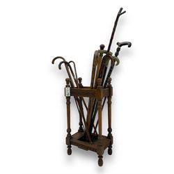 Early 20th century oak stick stand, rectangular structure with decorative carving, square base fitted with tray, on turned supports topped with finials; twelve assorted walking canes 