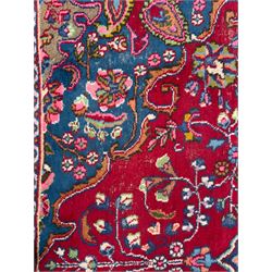 Pair of Persian wool rugs, each with rich red ground, one centred with a diamond-shaped medallion and navy spandrels within a floral field, the other with radiating floral medallion and scrolling foliate motifs, both enclosed by multiple borders with palmette and flowerhead designs, from the region of Kashan 291x376, 299 x 378 