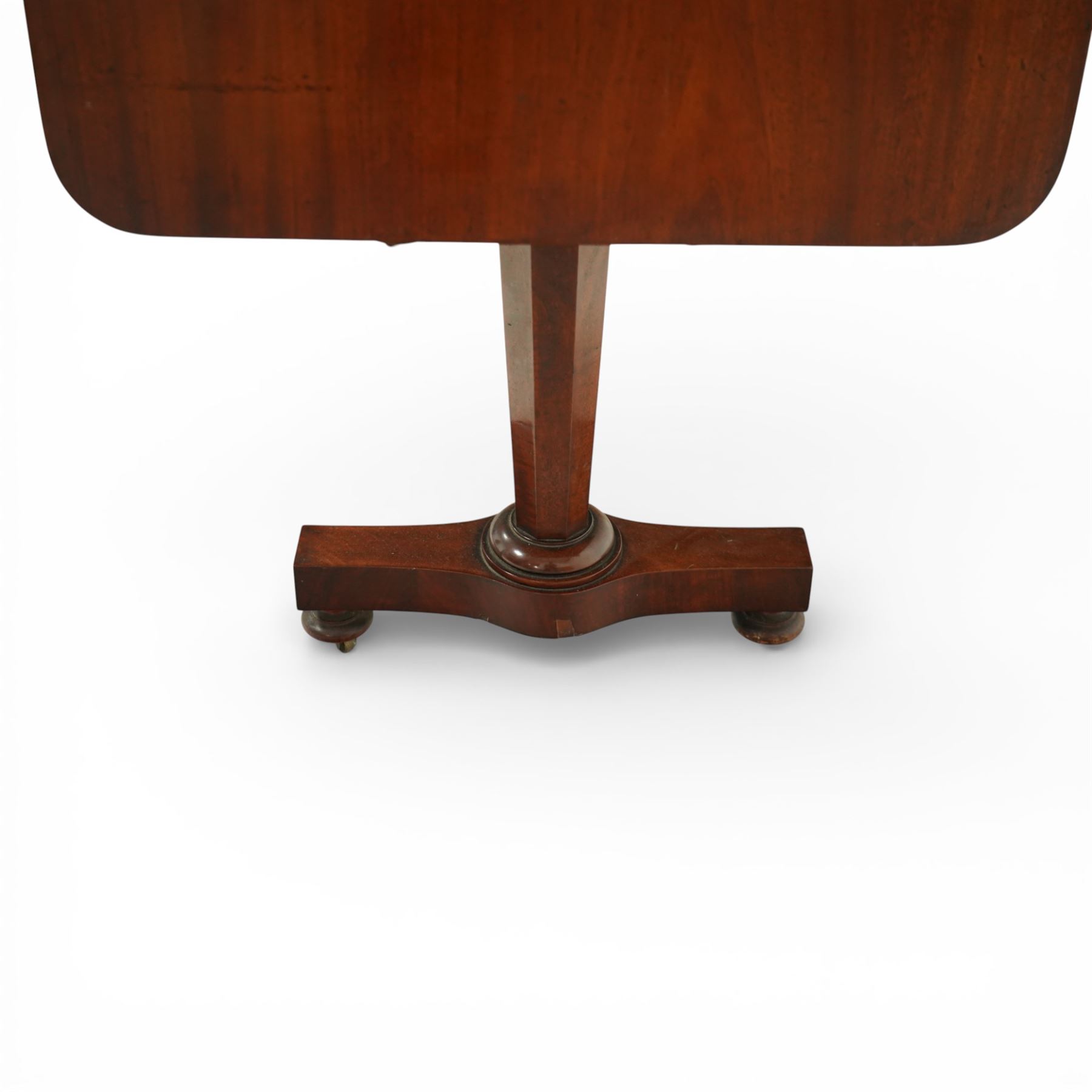 William IV mahogany sofa table, the rectangular top with rounded corners and hinged drop leaves to either end, above a shallow frieze fitted with two drawers opposing conforming dummy drawers, supported on octagonal tapering legs with ring turnings, joined by a shaped stretcher and raised on platform bases with scroll feet