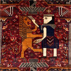 South West Persian Qahqai pictorial hand-knotted rug, madder red field with an all-over pattern of repeating rosettes enclosed with angular leaves and corners with stylized animals figures, central stylized lion in rearing stance and raised forelegs and a human figure shown in profile within a principal border of alternating octagonal and diamond medallions, each enclosing stylized rosettes, flanked by guard stripes incorporating latch hook motifs, with cotton fringe ends  