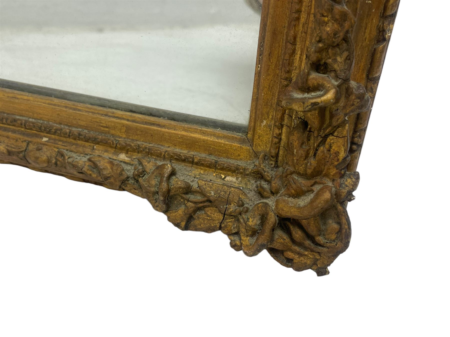 19th century gilt framed wall mirror, the corners decorated with flower heads with extending foliage, plain mirror plate