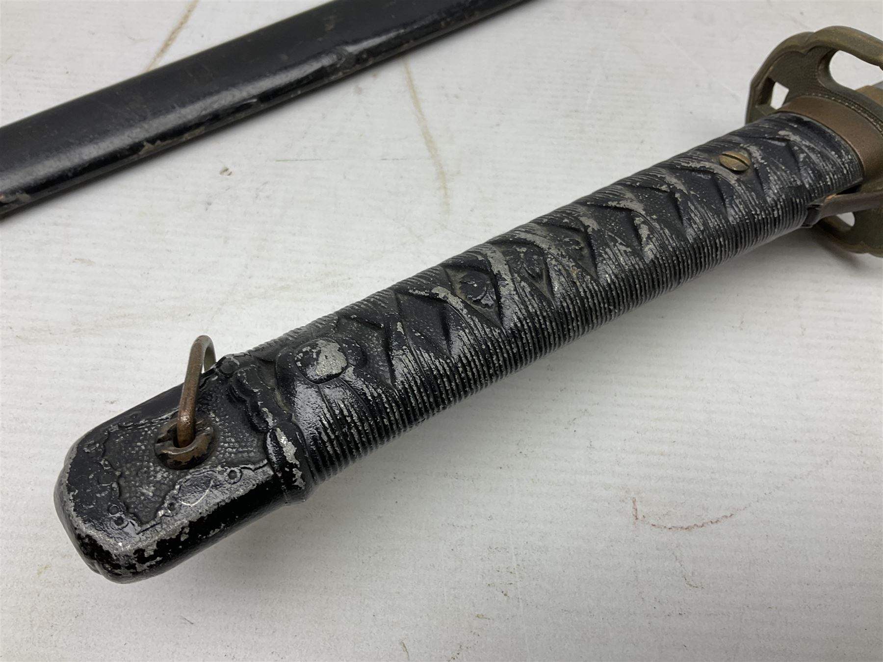WW2 Japanese Army NCOs sword - katana, the 69.5cm slightly curving fullered blade numbered 14656; arsenal markings stamped near the habaki on the handle; brass tsuba and black painted metal hilt cast to simulate cord bound fish skin; in black painted steel scabbard with single suspension ring L96cm overall