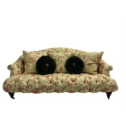 Victorian style three seat sofa, upholstered in beige ground floral floral pattern fabric, with scatter cushions, turned feet with brass castors