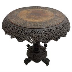 Late 19th century Anglo-Indian carved hardwood occasional table, circular tilt-top carved profusely with mythical animals and foliage decoration, pierced and carved with interlaced leafy branches, leaf carved pedestal supports on a raised platform with further carved and pierced foliage decoration, four carved feet in the form of mythical beasts with gaping jaws 