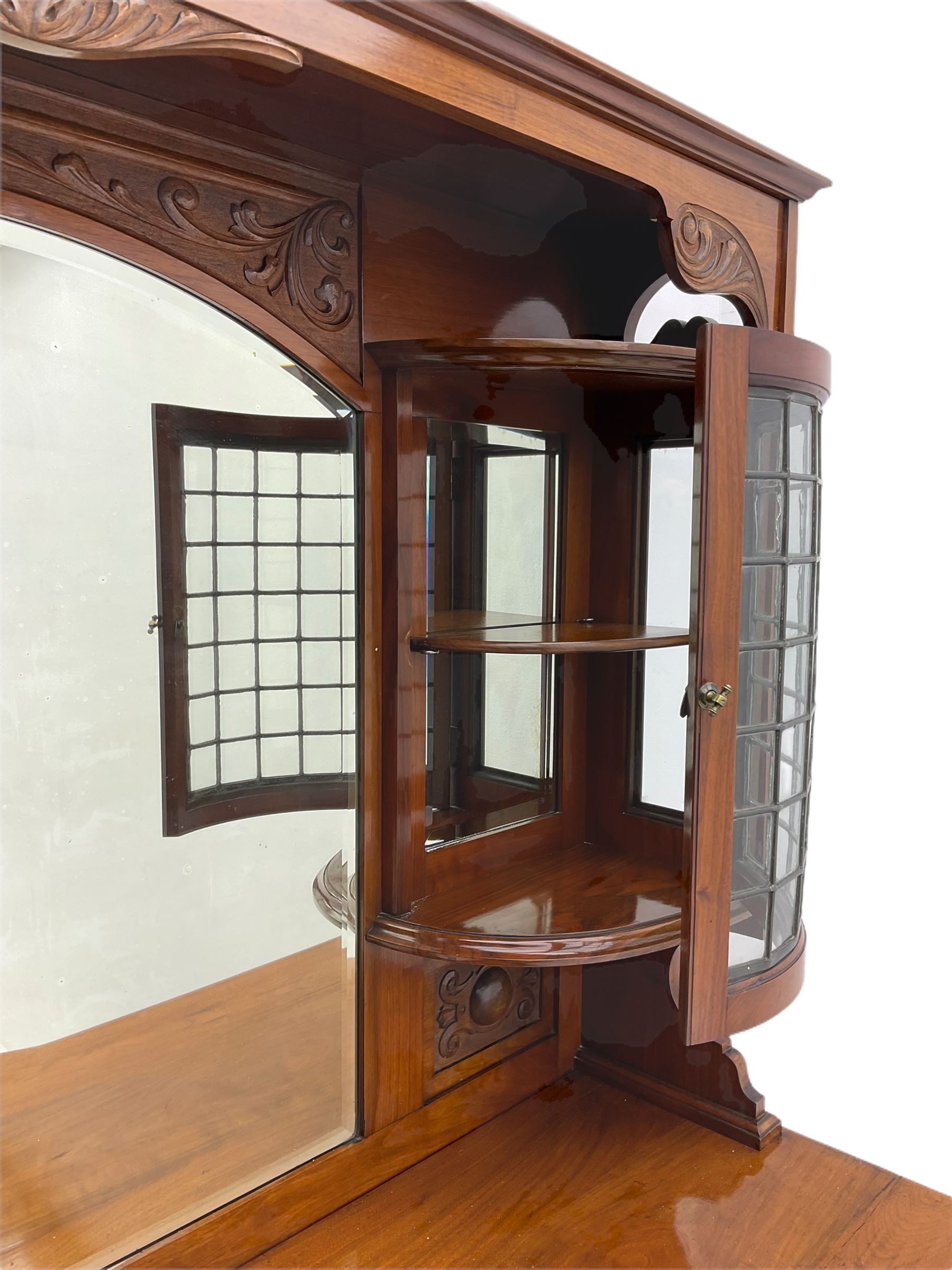 Late Victorian walnut mirror back sideboard or dresser, the raised back fitted with two curved and lead glazed cabinets, central arched bevelled mirror, the sideboard with break bowfront, fitted with six drawers and two cupboards, the cupboard doors panelled and carved with scrolls, shell and plant motifs, shaped apron with cabriole feet
