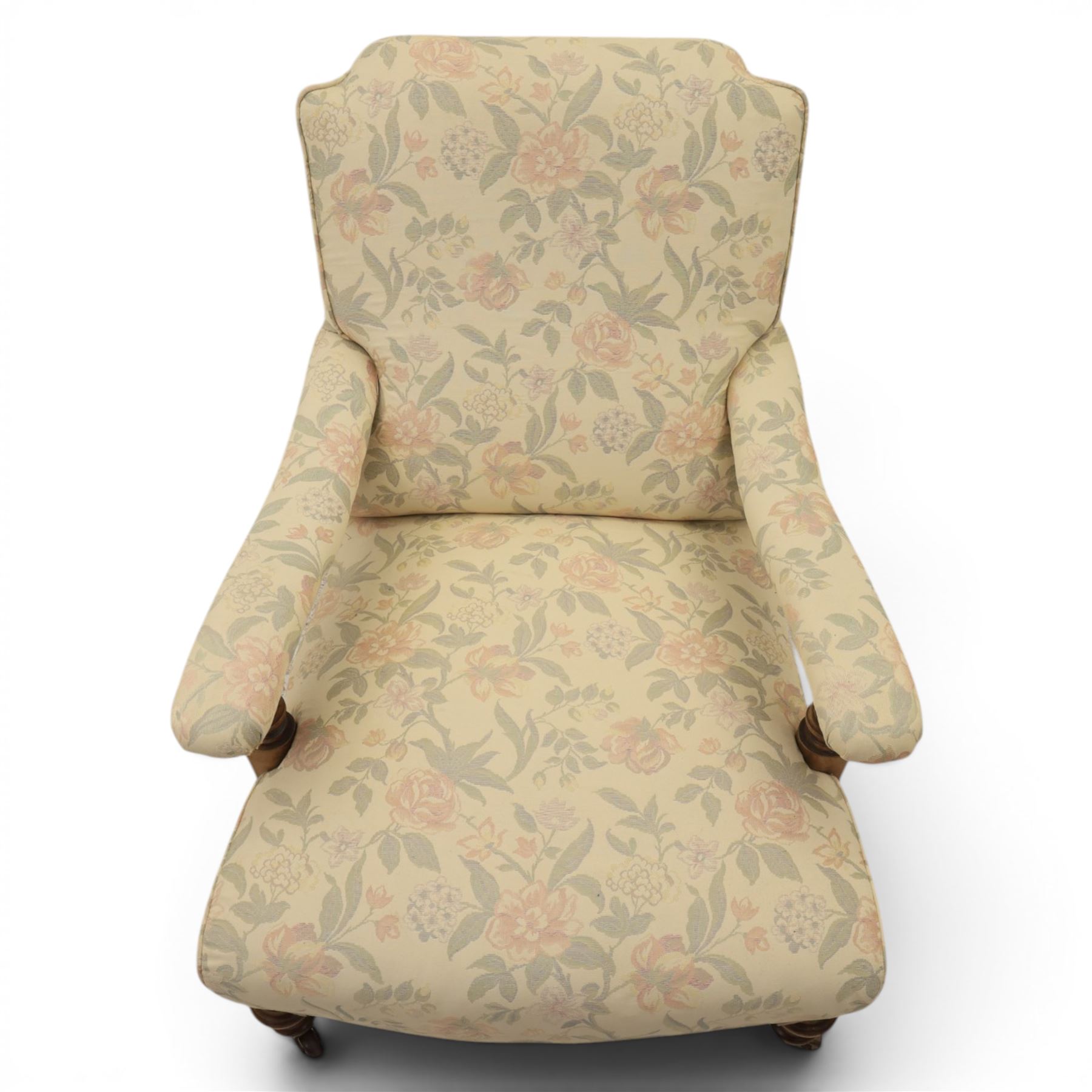 Victorian mahogany framed deep seat low drawing room chair, upholstered in beige floral fabric, on turned supports terminating in castors