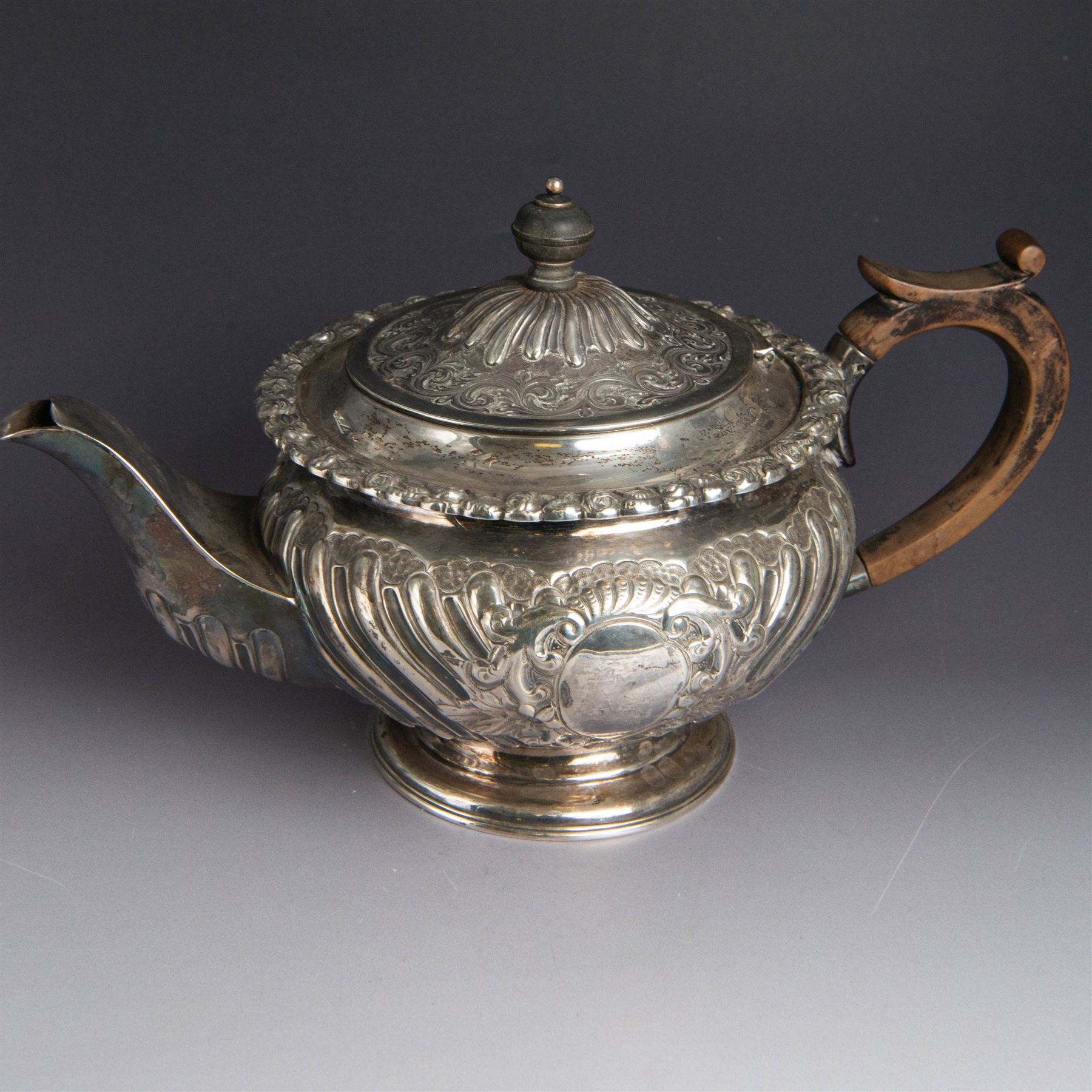 Victorian silver four piece tea service, comprising hot water pot, teapot, milk jug and sugar bowl, of circular part fluted bellied form, with embossed and engraved floral decoration, engraved with initials to body, the teapot and hot water pot with wooden handles and finials, hallmarked Z Barraclough & Sons, Sheffield 1898