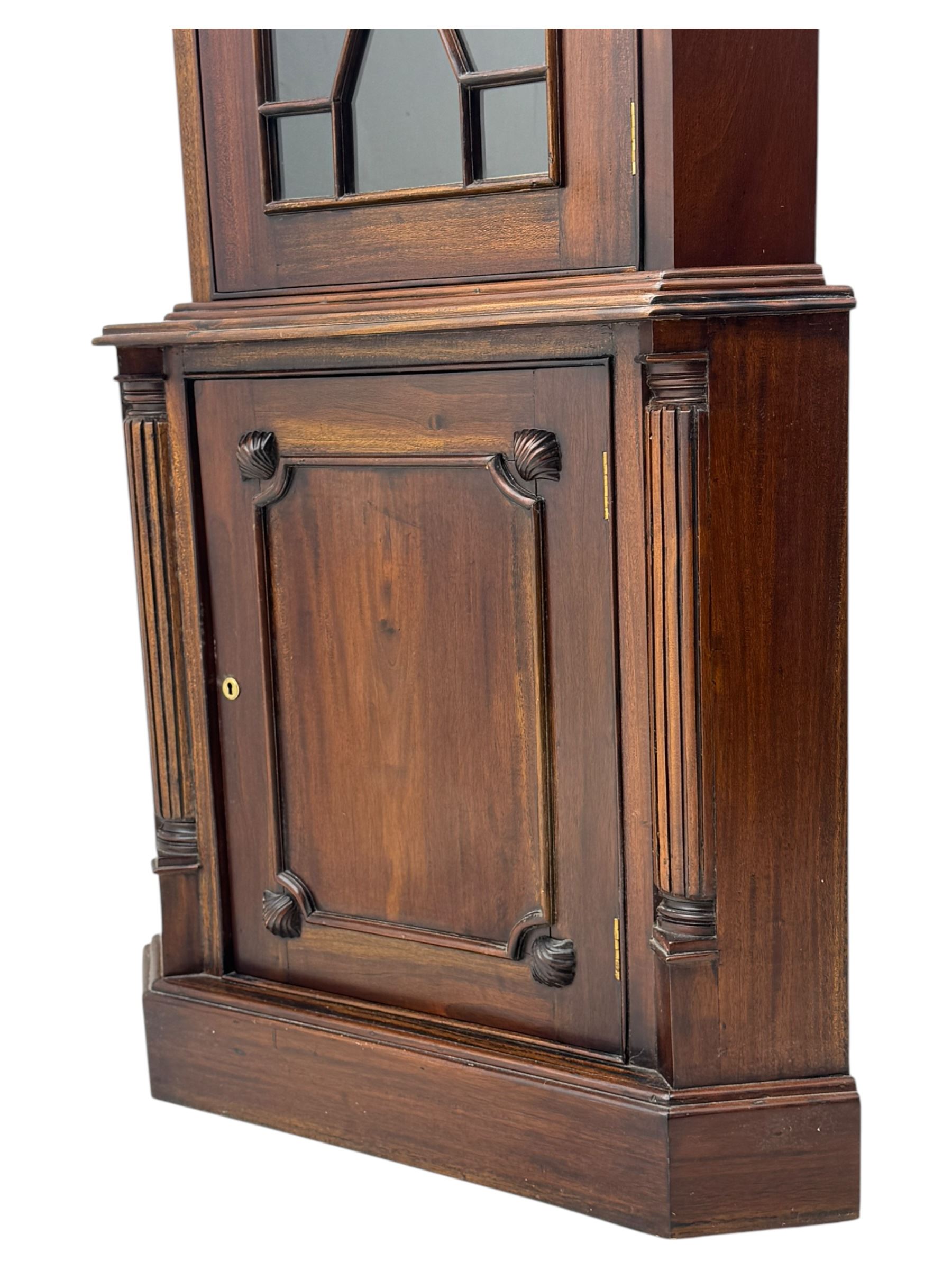 Late 20th century mahogany corner cabinet, dentil moulded cornice above a glazed door with astragal glazing enclosing two shelves, lower cupboard with fielded panel door and turned shell motif, on plinth base