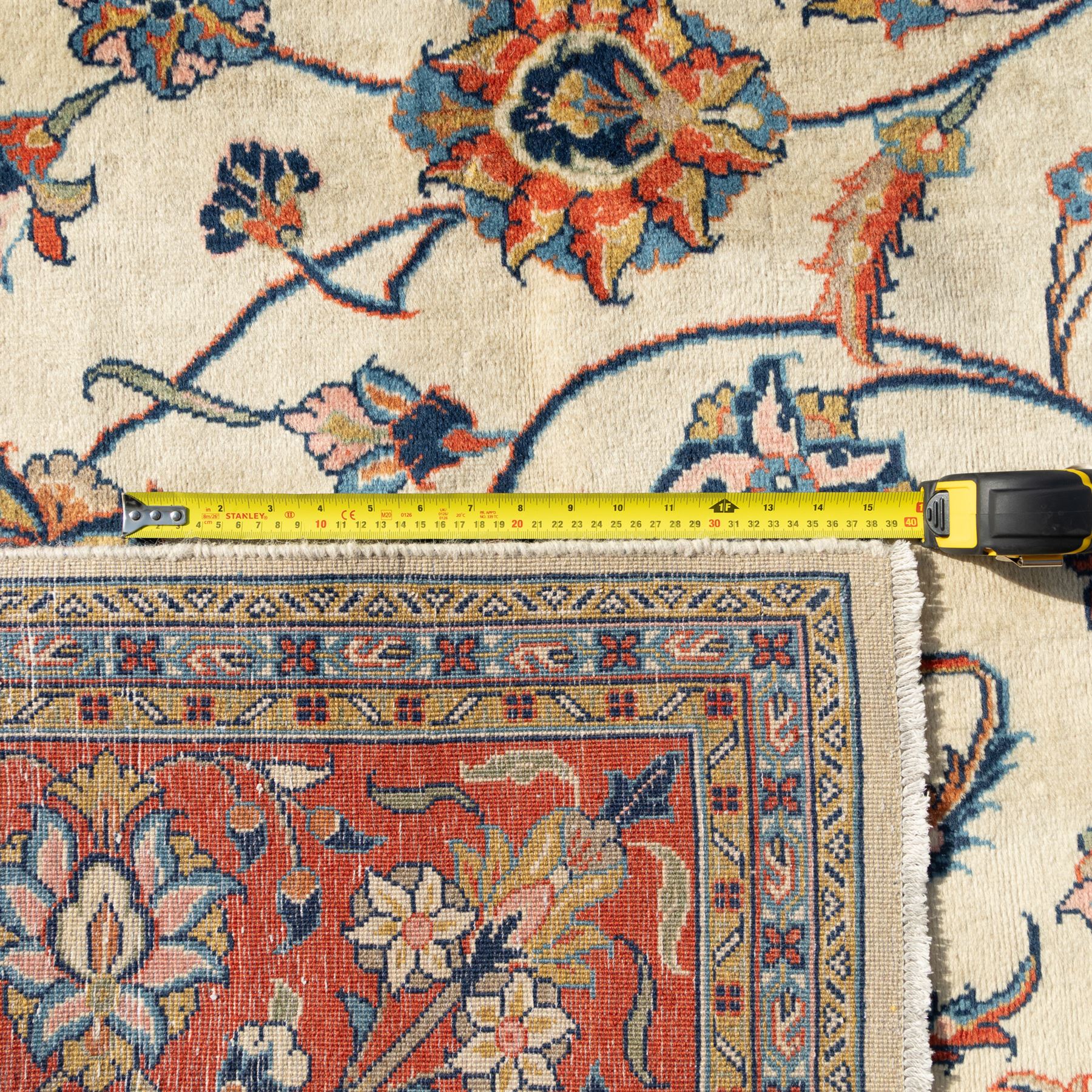 Persian Sarough carpet, ivory field with symmetrical arrangement of scrolling vines, palmettes and floral sprays in red, blue and green, enclosed by a broad red main border with repeating floral motifs, originating from the Arak region of Iran