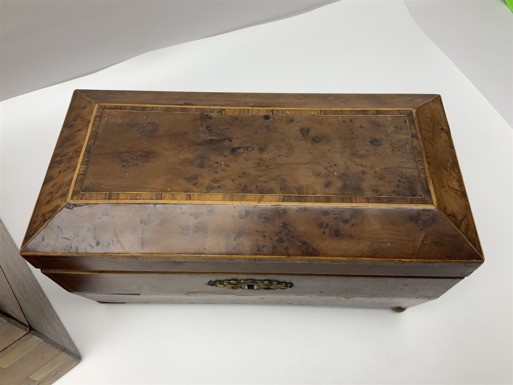 19th century burr yew wood tea caddy, of sarcophagus form, with strung details and brass mounts, the interior split into three compartments, upon four brass bun feet, together with an oak and brass bound writing slope, with red leather interior with gilt detailing, largest H16cm, W40cm