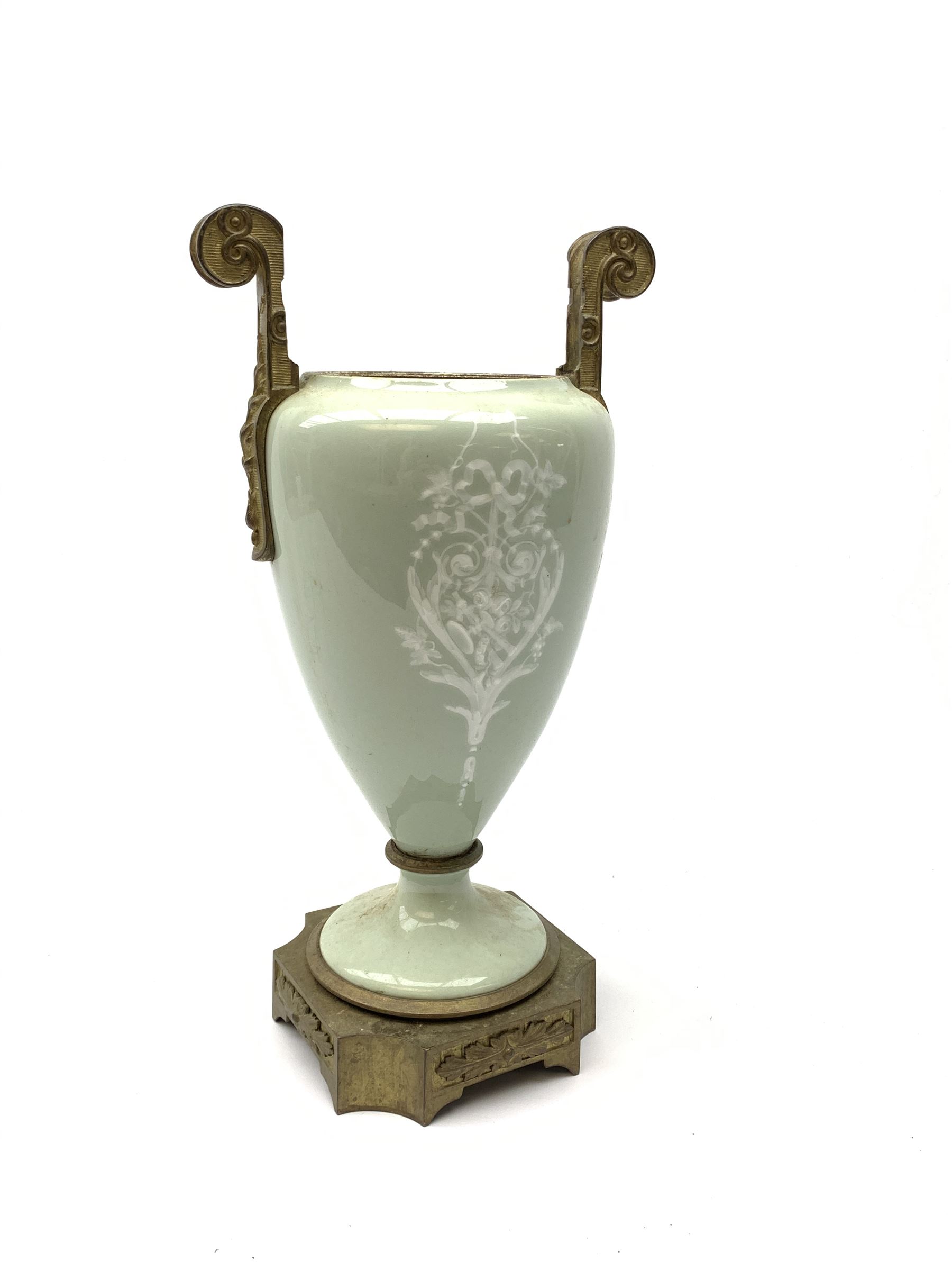 A pate sur pate celadon green vase, of baluster form decorated with a classical female figure to one side, and floral swag with ribbon and musical trophy to the other, with twin gilded scroll handles, and raised upon a gilded base, overall H38.5cm. 