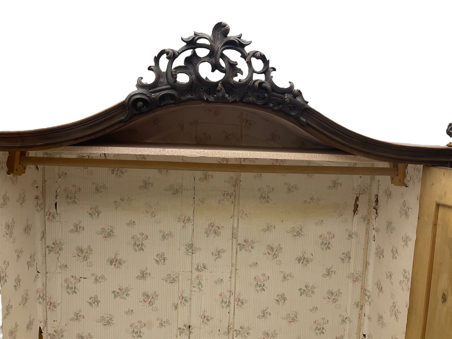 Early 20th century Italian walnut armoire wardrobe, the pierced and scrolling pediment carved with acanthus leaf detail, flanked by two scrolling cartouche with matching corbels below, the two panelled doors with applied carved rinceaux slips, with a central spiral turned upright, enclosing single shelf and hanging rail, raised on scroll feet