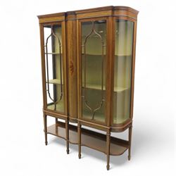Edwardian inlaid mahogany display cabinet, projecting moulded cornice over two glazed doors, flanked by curved glazed sides and central arched panel with floral medallion, raised on square tapering supports with spade feet united by undertier