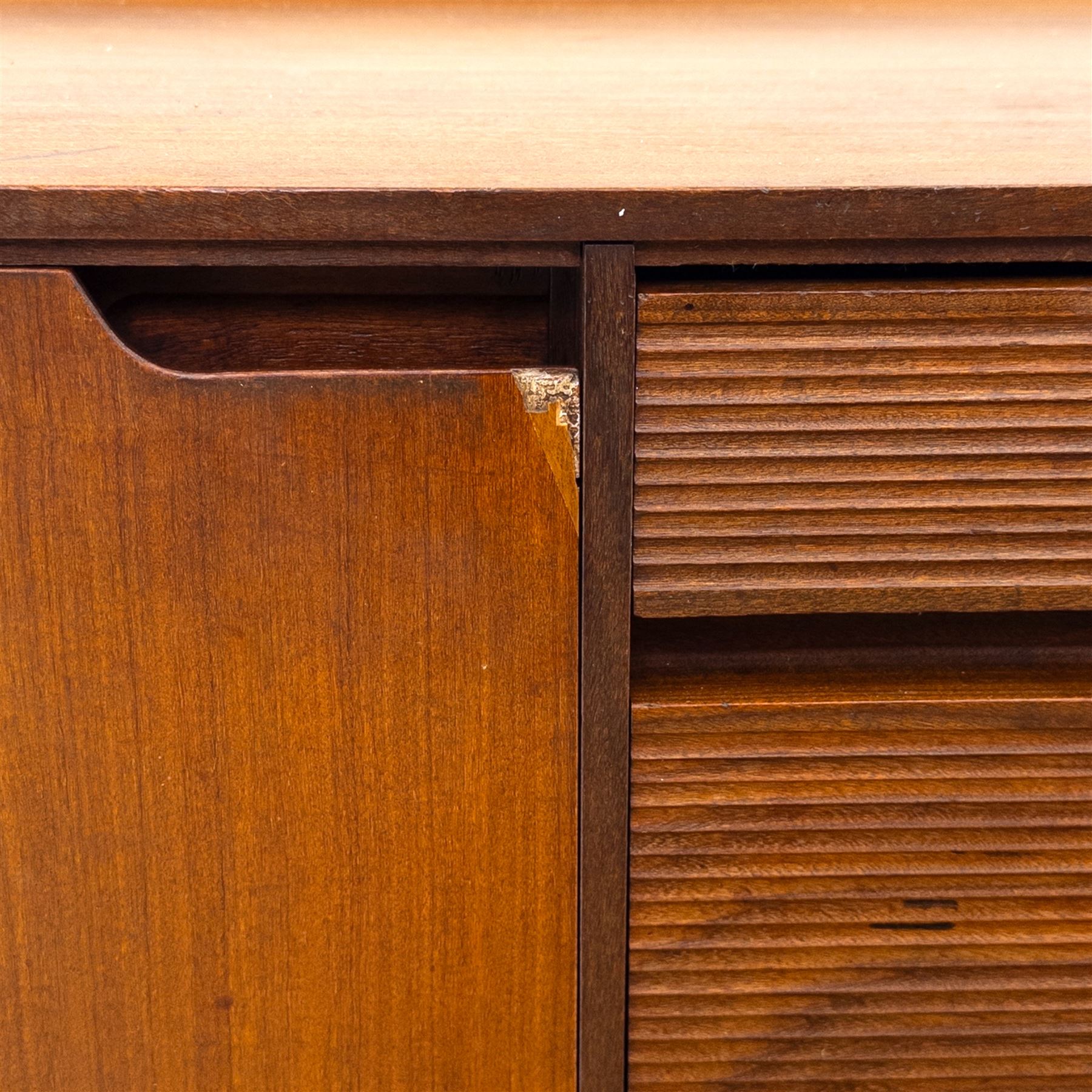 Richard Hornby for Fyne Ladye - mid-20th century afromosia teak sideboard, retailed by Heals of London, rectangular form, with low profile carved gallery lip, above three central drawers with ribbed drawer fronts, flanked by two cupboards with vertically grained doors and recessed pull handles, with streamlined moulded edges and sides, raised on tapered slender legs 
