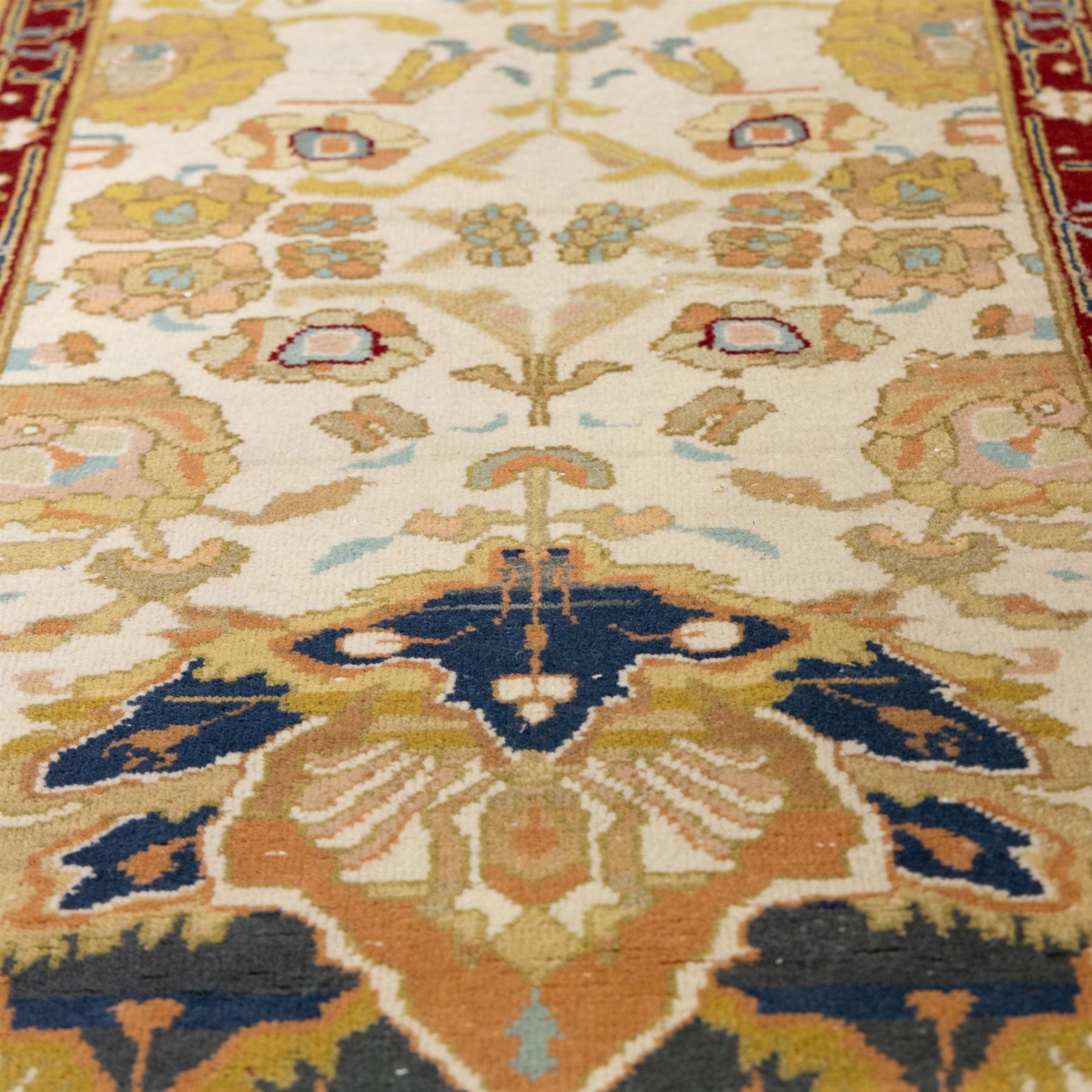 Agra wool runner, cream field decorated with large stylised palmettes, scrolling vines and flowerheads, enclosed by red main border with foliate motifs and fringed ends
