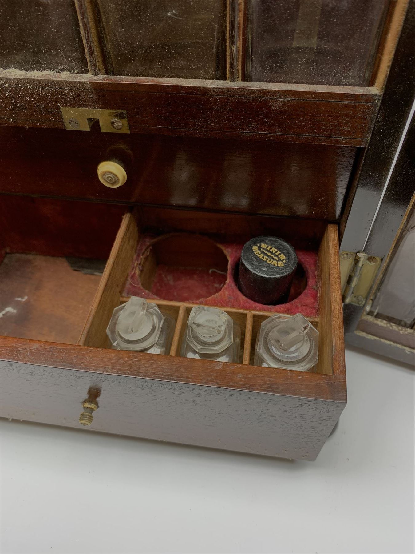 19th century mahogany travelling apothecary cabinet, with recessed brass carry handle to top, and two deep-section hinged doors to the front opening to reveal a fitted interior with clear glass bottles and two drawers, H27cm