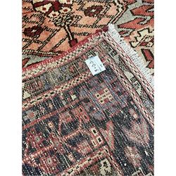 Persian Heriz red ground rug, the field decorated with three medallions, decorated all over with stylised and geometric motifs, triple band border 