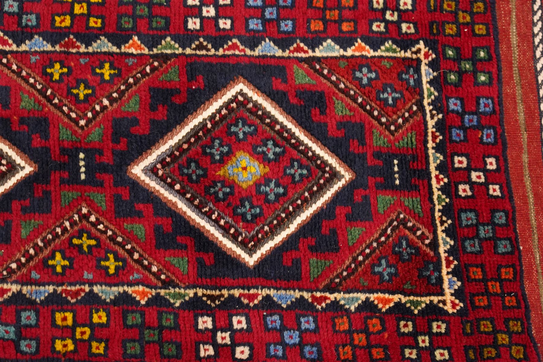 Two hand-knotted rugs, comprising Persian runner and Turkoman prayer rug, Persian hand-knotted runner, red and dark navy ground with four diamond medallions and geometric motifs, enclosed by multicoloured geometric border, striped kilim ends with fringes, H244cm, W58cm; Turkoman hand-knotted prayer rug, ivory mihrab field decorated with repeating stylised geometric motifs, enclosed by multiple geometric borders in madder red and brown, with fringed ends, H150cm, W93cm