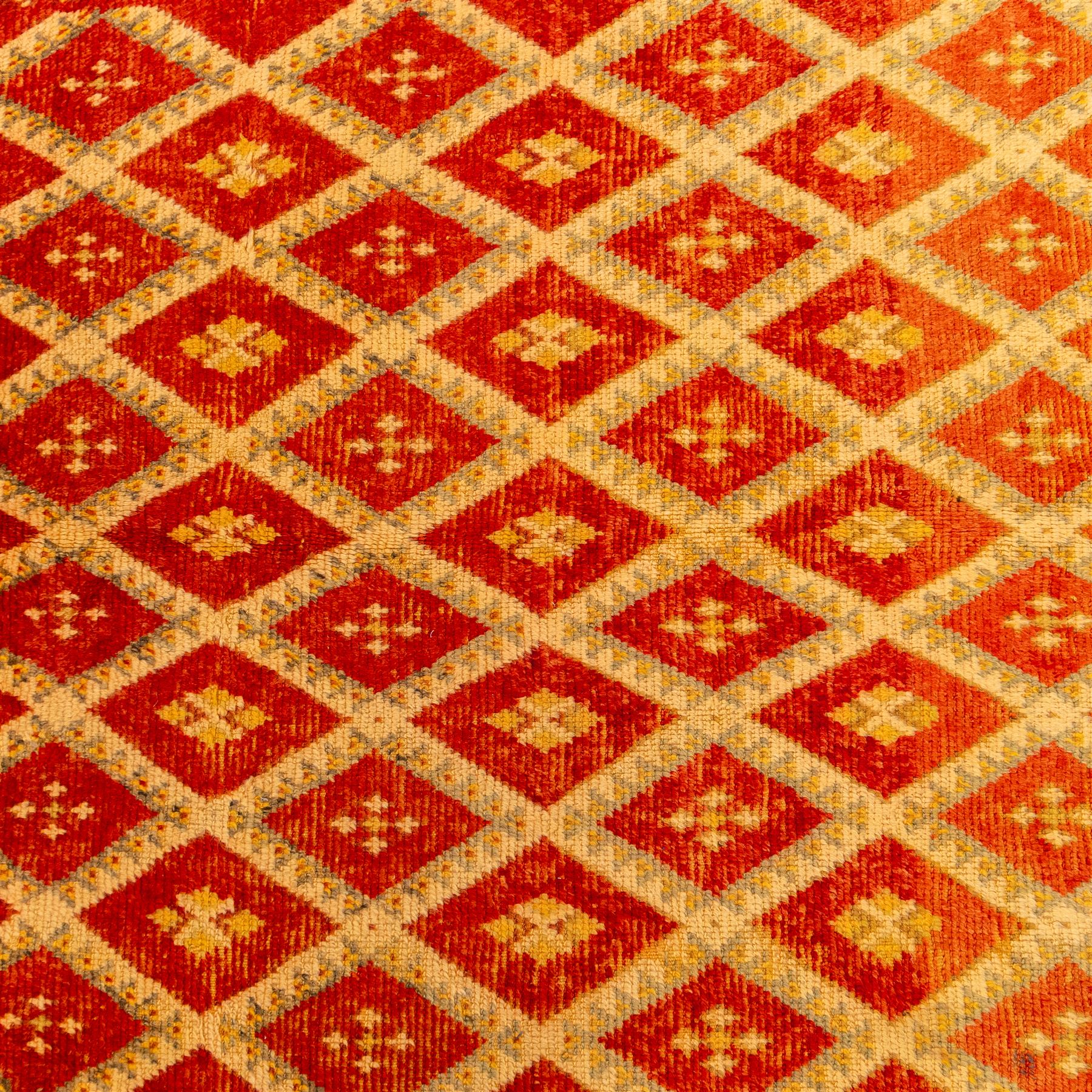Moroccan Berber hand knotted runner, the red and orange ground woven with an all over lattice of lozenge motifs enclosing small geometric devices, within narrow patterned borders, finished with fringe to one end