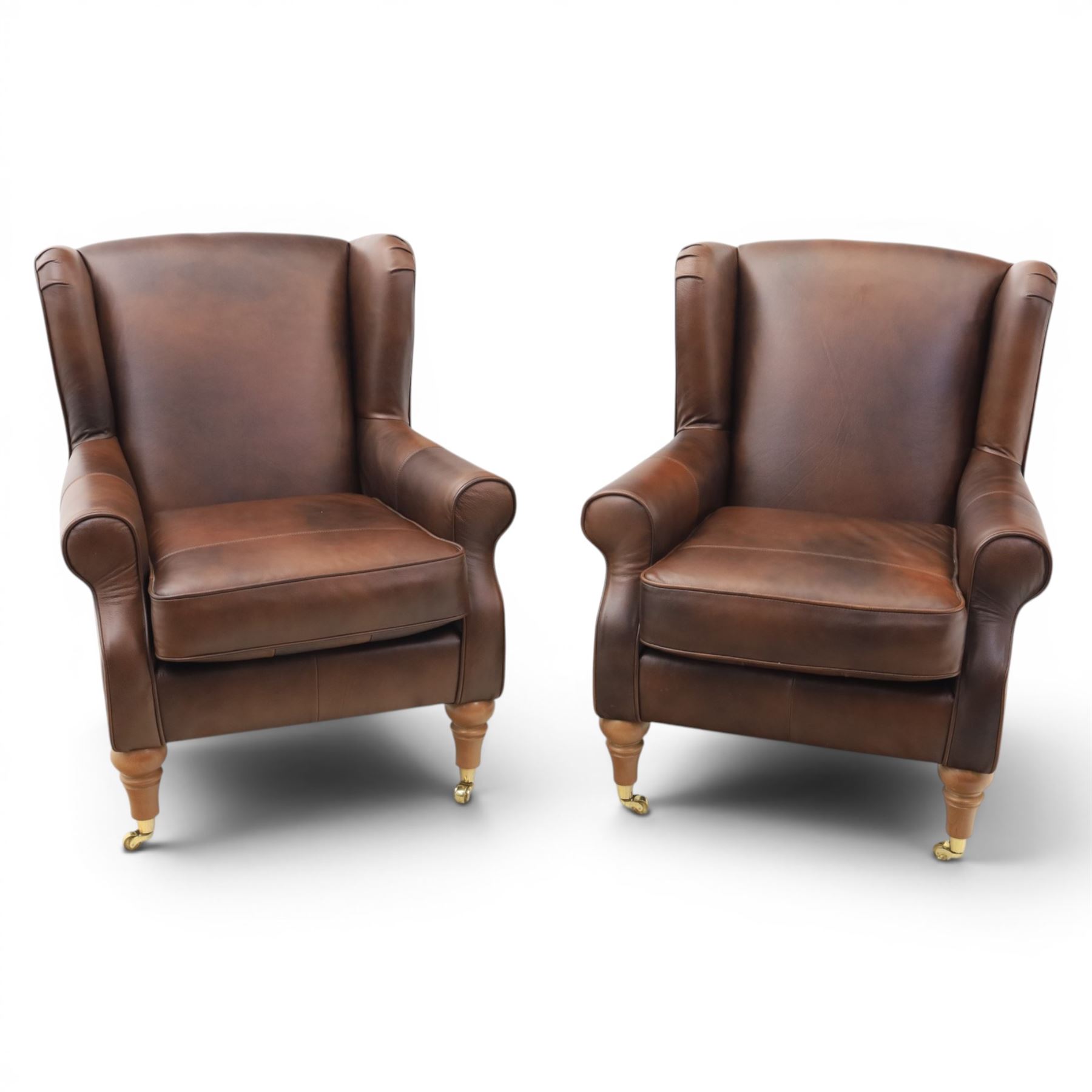 Marks & Spencer - Pair of brown leather wing back chairs, raised on light stained supports with castors
