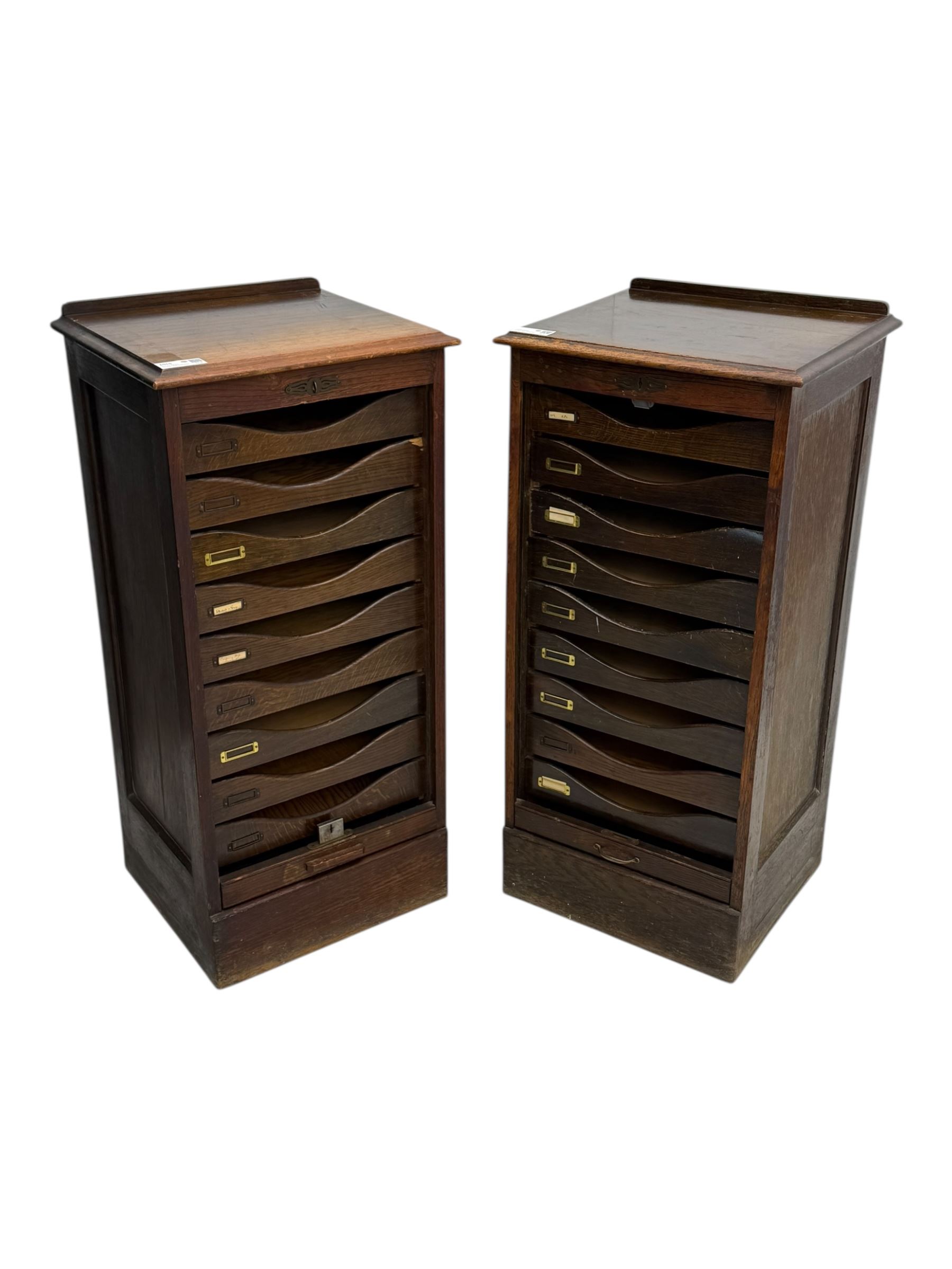 Two early 20th century mahogany tambour cabinets, each with retractable roll-top front revealing fitted interior with concave-front filing drawers and brass fittings
