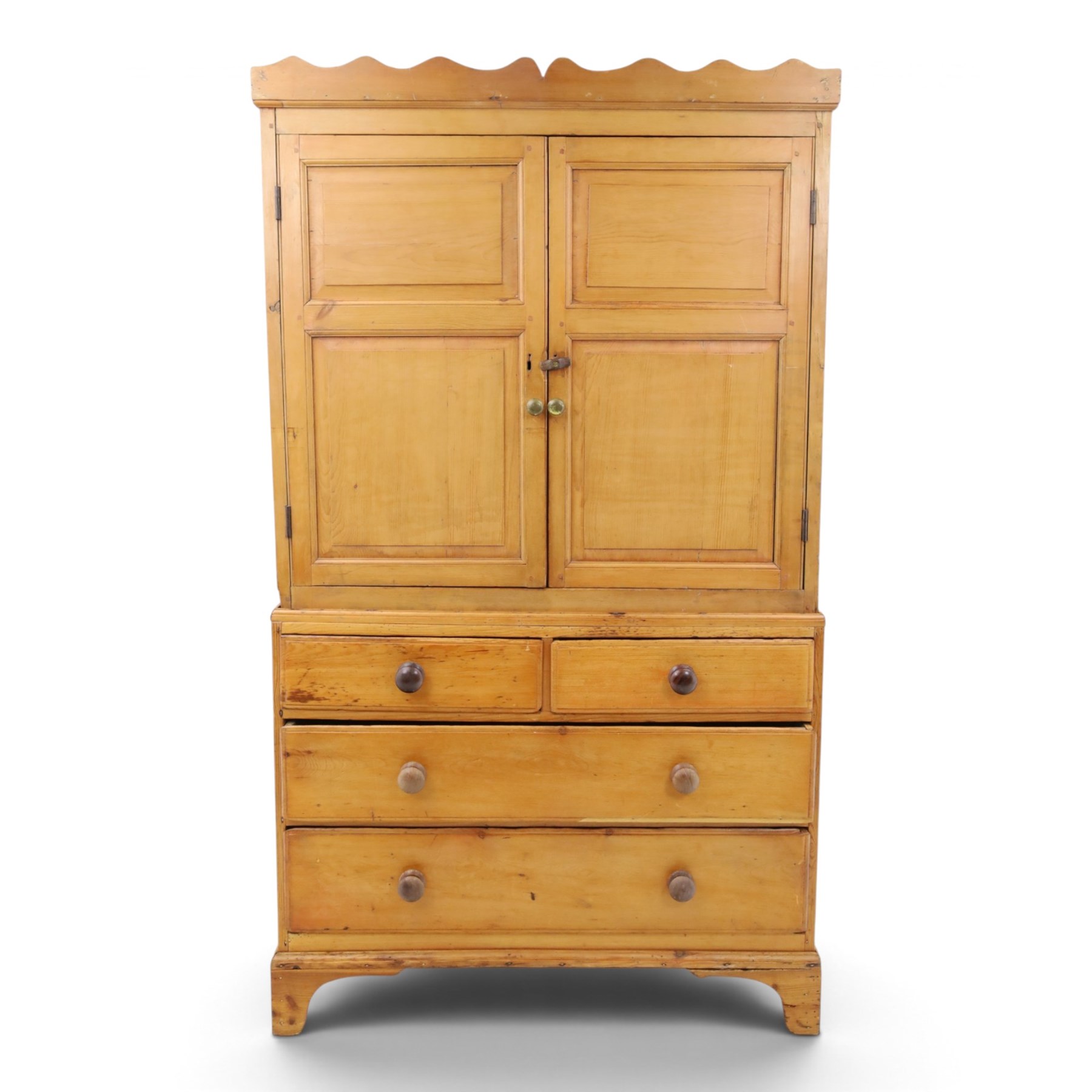 19th century waxed pine press cupboard, shaped cornice above a twin fielded panelled cupboard door enclosing a fixed shelf, the lower section two short two long drawer