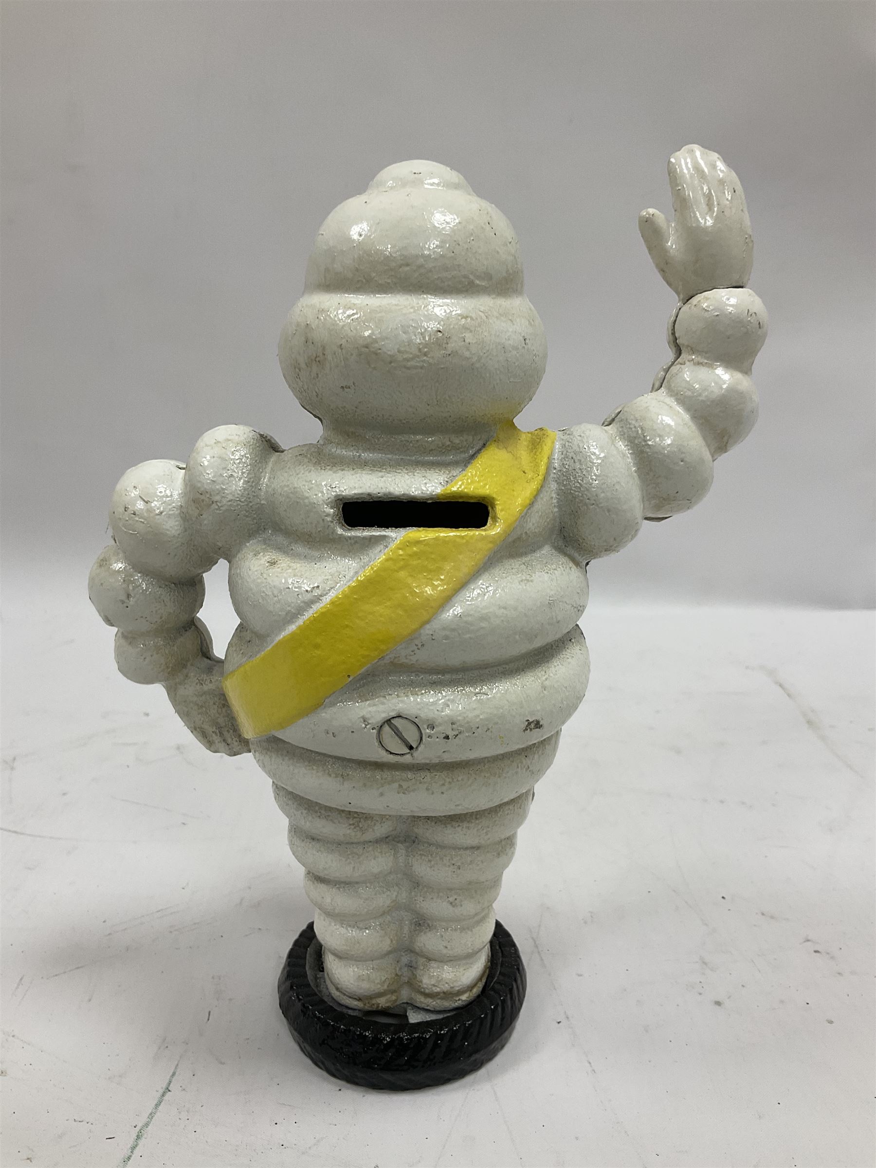 Cast iron money bank of a waving Michelin man stood on a tyre, H23cm