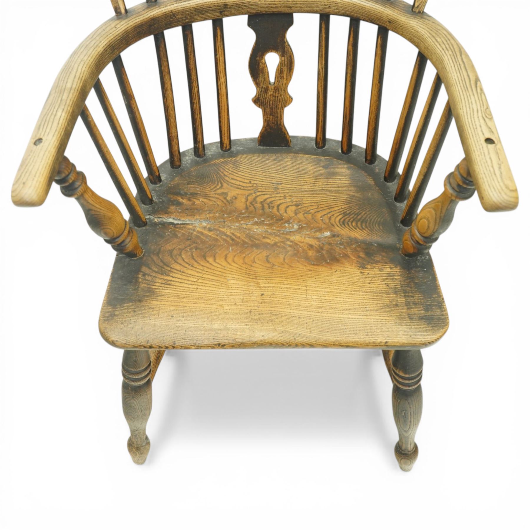 19th century low back elm Windsor armchair, hooped back with pierced central splat and radiating spindles, shaped arm bow over saddle seat, on turned supports