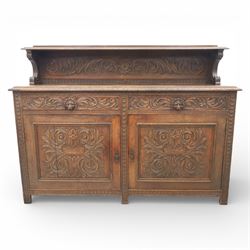 Victorian carved oak sideboard, the rectangular top with raised back carved with foliate scrolls and scroll end supports, upon a base with rectangular top with moulded edge, pair of drawers with conforming carved decoration and mask handles, and pair of carved cupboard doors, upon short stile type feet H101.5cm W183cm D54cm 