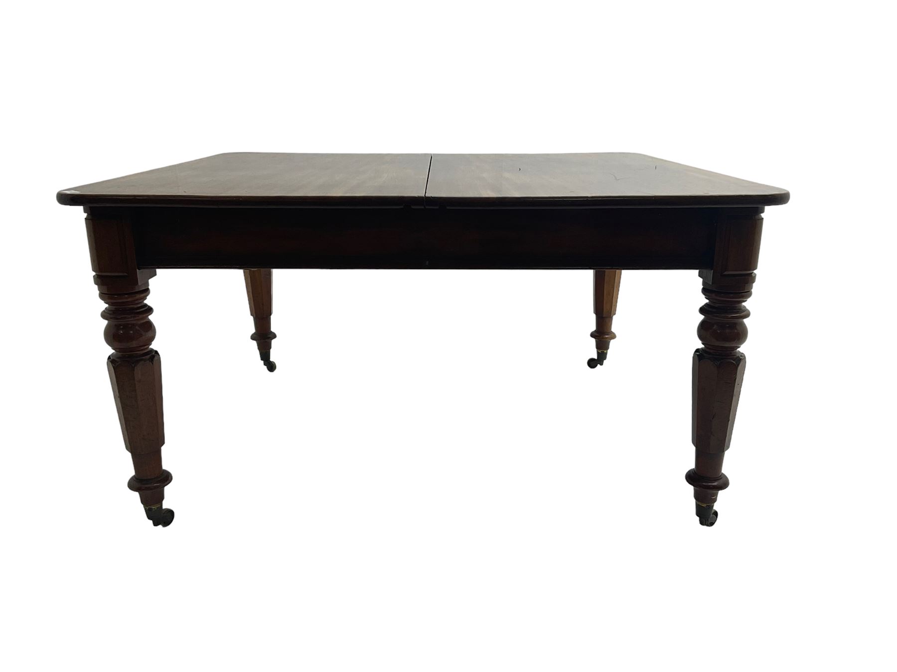 Late 19th century extending mahogany dining table, square top with banded frieze rail, raised on turned octagonal supports with  brass cups and castors, with two additional leaves