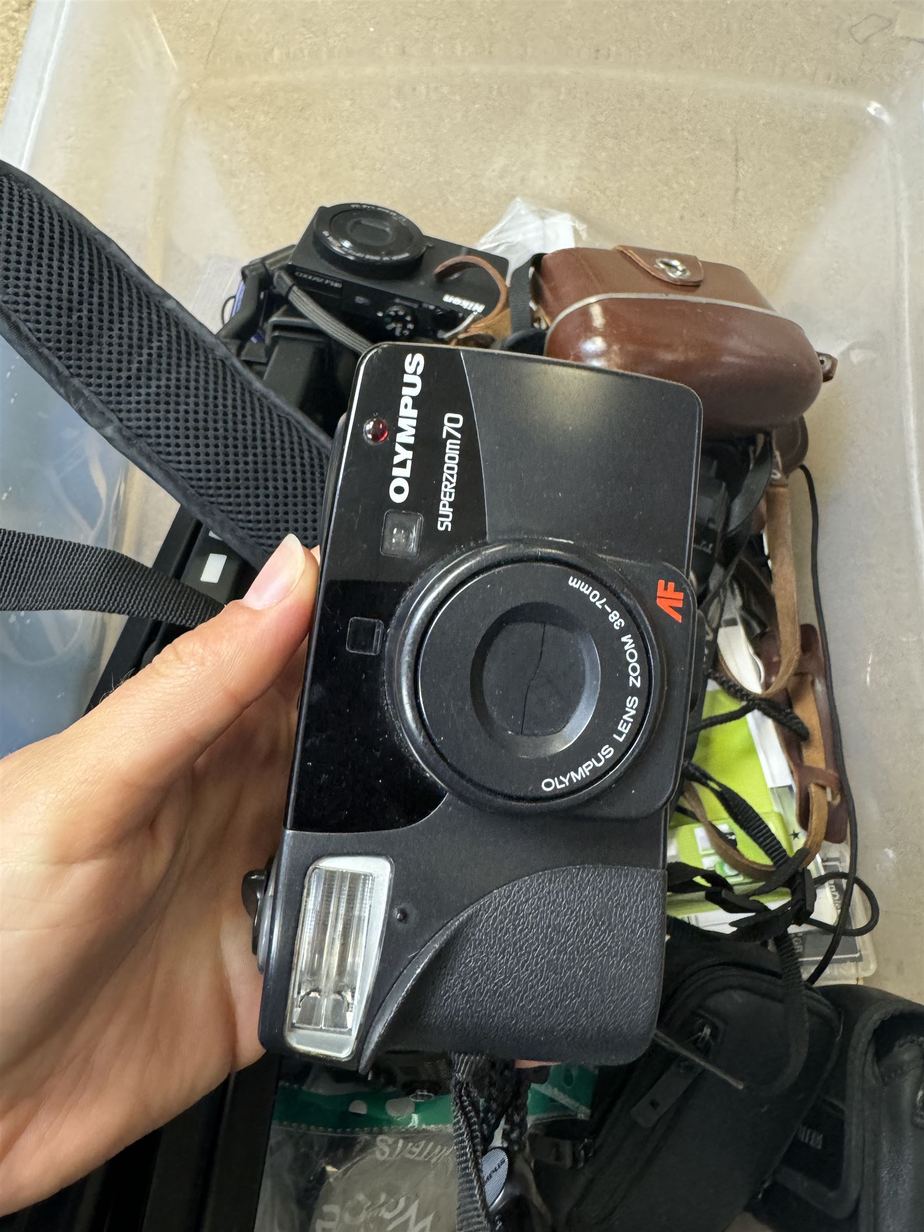 Collection of cameras and camera equipment, including Voigtlander Vitomatic I, Nikon Coolpix P340, Nikon Coolpix S9100, Olympus SP-510UZ, tripod, cases, etc